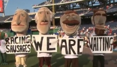 The Washington Nationals Presidents racing presidents hold up signs taunting the Milwaukee Brewers racing sausages